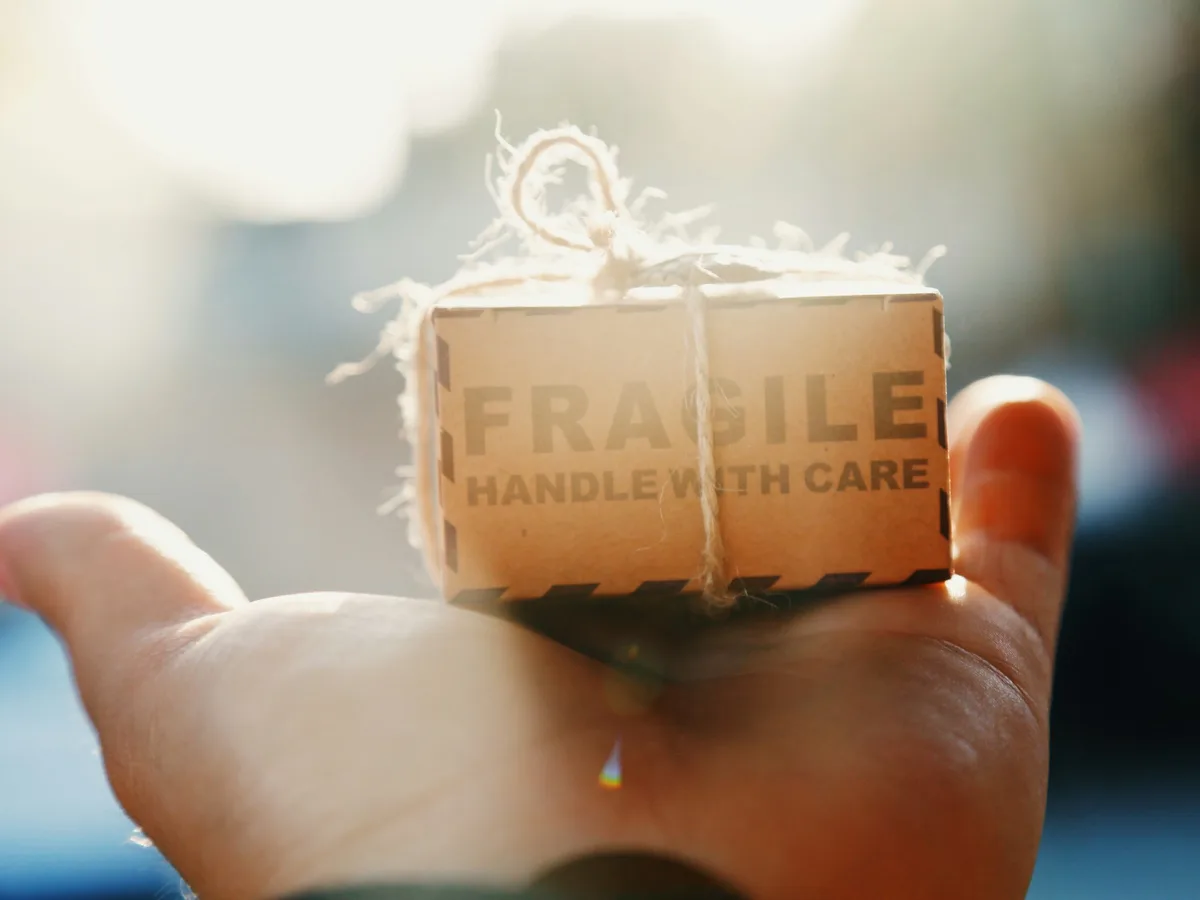 Hand holding a small parcel marked Fragile, handle with care